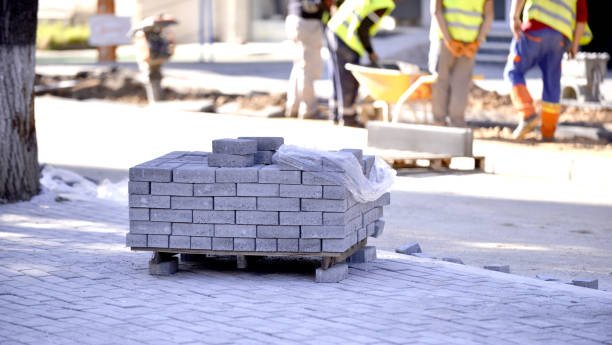 Group of men standing beside a large pile of bricks, presenting construction materials for commercial walkway construction in Maybel, GA.