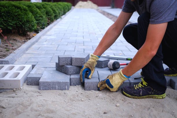 A skilled worker from Big D's Concrete LLC carefully lays bricks to create a new walkway, showcasing expert patio and walkway installation in Atlanta, GA.
