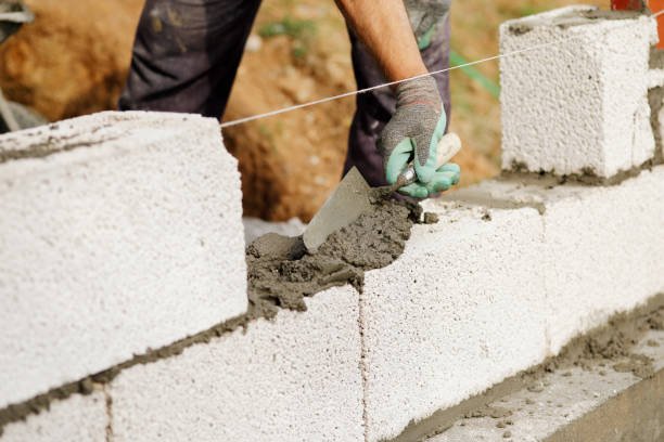 Craftsman using a trowel to build a decorative concrete wall, showcasing skilled craftsmanship in constructing sturdy walls.