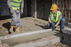 Two concrete contractors in Atlanta, GA are applying concrete to a floor at a construction site.