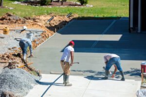 A team of concrete contractors in Charlotte, NC working on a construction site, pouring concrete and using tools.