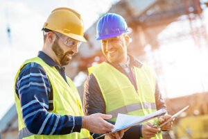 Two local concrete contractors in Dallas, GA wearing hard hats and safety vests inspecting a construction site.