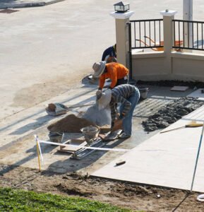 A team of concrete contractors in Dallas, GA working together on a sidewalk installation, demonstrating expert collaboration and skill.