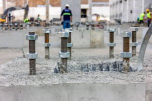 Concrete blocks with bolts arranged on a flat surface as part of a concrete foundation setup for structural support.