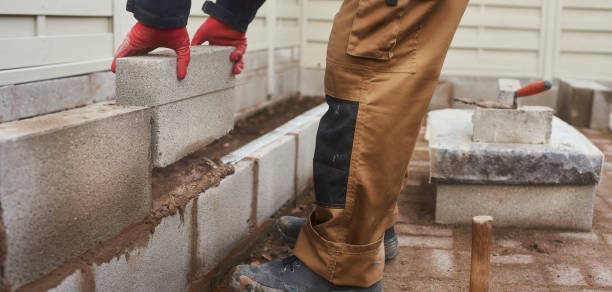A concrete contractor in Atlanta, GA carefully installing bricks for a custom residential wall project.