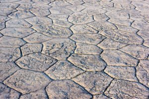 Close-up of a cracked stamped concrete patio, highlighting the texture and damage on the surface.