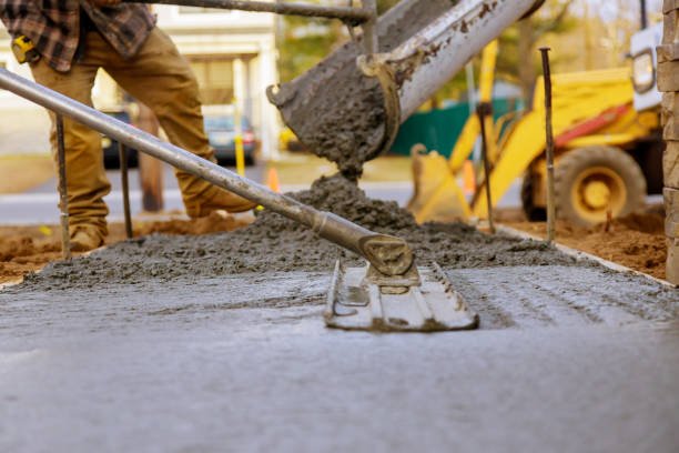 A man pouring concrete onto a sidewalk, showcasing concrete services in Mableton, GA.