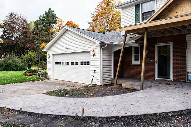 A driveway featuring stamped concrete, leading to a garage and a porch, showcasing a modern residential design.