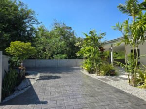 A concrete driveway with a stamped walkway and trees on either side, enhancing the landscape's aesthetic appeal. 