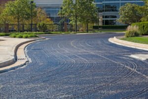 An asphalt road is being paved, showcasing a commercial driveway paving operation in progress.