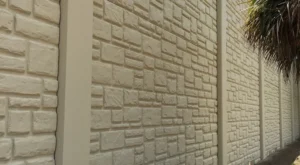 Beige textured stone-patterned decorative concrete wall with vertical concrete pillars.
